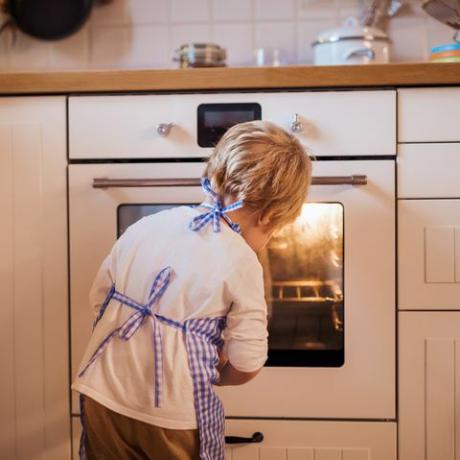 Garotinho olhando no forno dentro de casa, assar