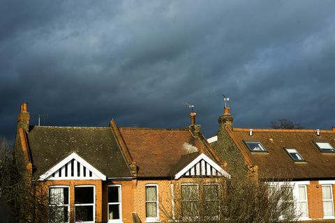 Ameaçando nuvens sobre casas iluminadas pelo sol