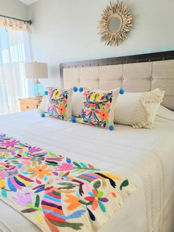 um dormitório desenhado por soluna paz apresenta bordado otomi em um cobertor e um par de travesseiros