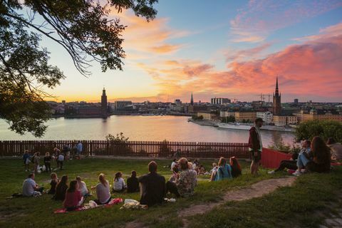 Pessoas fazendo piquenique em um parque com panorama de Estocolmo durante o pôr do sol, Suécia