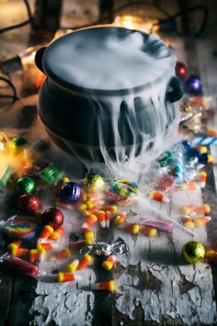 vista de alto ângulo da panela com fumaça em meio a doces espalhados na mesa durante o halloween