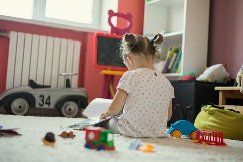 Menina lendo livro na sala de crianças.