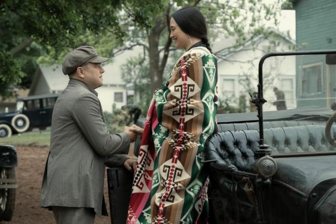 um homem e uma mulher parados ao lado de um carro com um lenço decorado