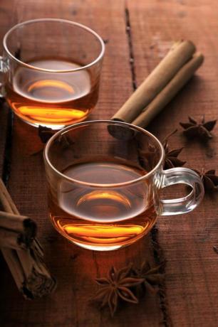 chá de ervas com anis estrelado e canela em uma xícara na mesa de madeira