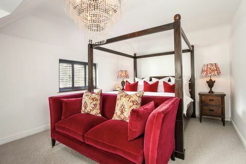 quarto branco com cama de dossel e sofá vermelho