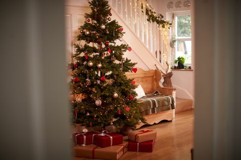 Corredor da casa decorada para o Natal com árvore e presentes vistos através da porta aberta