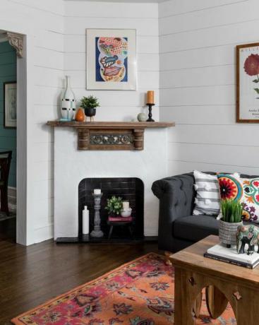 sala de estar, piso de madeira, tapete, mesa de centro de madeira, lareira de ladrilhos de metrô branca e preta, sofá cinza escuro com almofadas coloridas