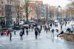 Patinadores no gelo deslizam sobre os canais congelados de Amsterdã durante o grande congelamento da Europa
