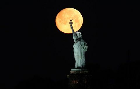 A lua se põe atrás da estátua da liberdade em Nova York
