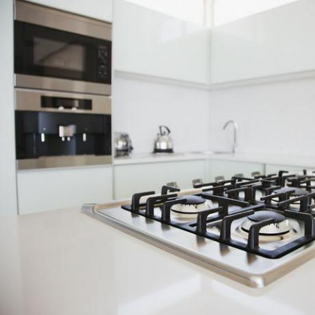 fogão e forno em cozinha moderna com armários brancos