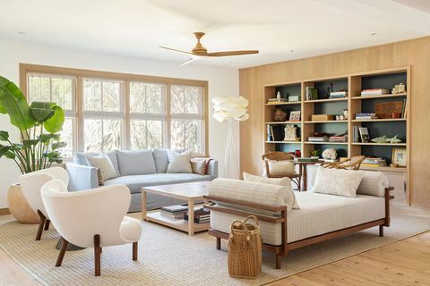 sala de estar, estante da biblioteca, espreguiçadeira branca com braços de madeira, sofá-sofá azul, poltronas brancas