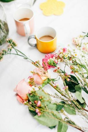 Mesa com flores cortadas e xícaras de café na oficina de organização de flores