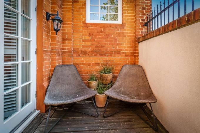 um pequeno terraço no pátio com duas cadeiras marrons