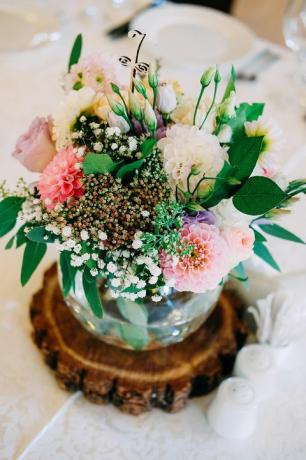 Decoração de flores de mesa de casamento. Vaso de vidro com o número da mesa para convidados com hortaliças, rosas, lisianthus e outras flores.