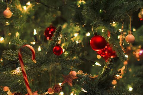 Fechar ornamentos e luzes da corda na árvore de Natal