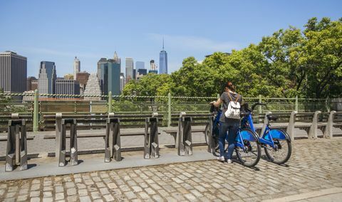 Mulher tomando uma bicicleta na frente do horizonte de Manhattan em Nova York