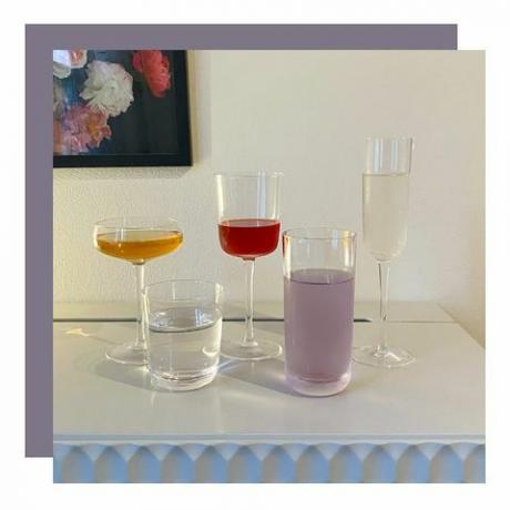 variedade de copos de diferentes formatos na mesa lateral com pinturas de flores penduradas na parede