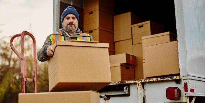 trabalhador masculino descarregando caixas de papelão da van de entrega