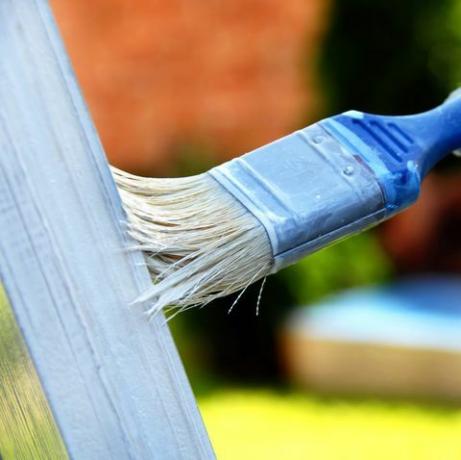 pincel na mão pintando porta de madeira ao ar livre