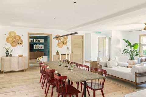 mesa de jantar, cadeiras de jantar vermelhas, espreguiçadeira branca, wats na parede, chapéus pendurados como arte, piso de madeira