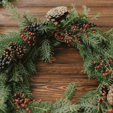 guirlanda de natal moderna com bagas vermelhas, galhos verdes, pinhas, decorações naturais para árvores em fundo rústico guirlanda de natal rústica na mesa de madeira Feliz Natal