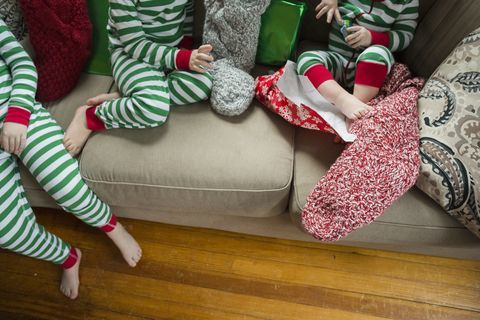 Foto sem rosto de irmãos abrindo meias em casa no Natal