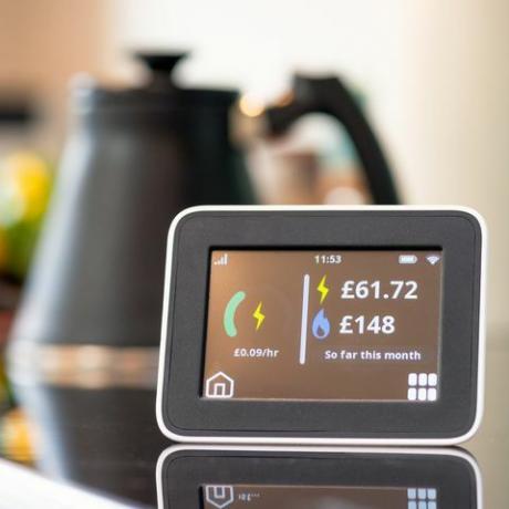 close-up da tela de um medidor inteligente em uma cozinha, mostrando o custo mensal de eletricidade e gás até o momento