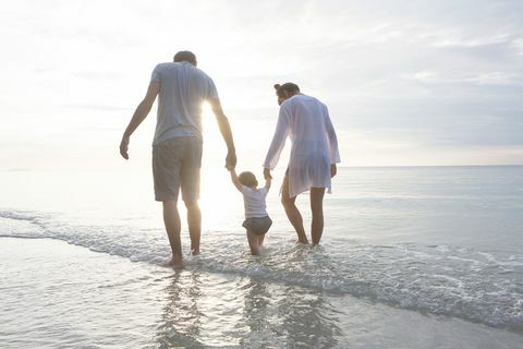 uma família de mãos dadas andando na praia