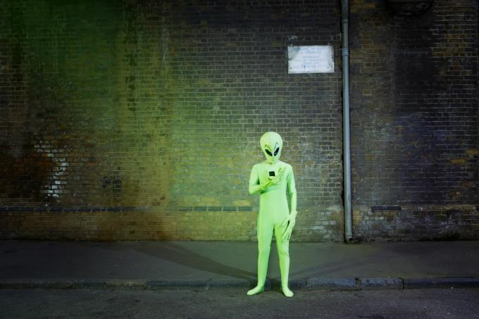 homem vestido com fantasia de alienígena olhando para celular