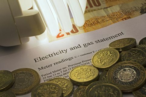 Declaração de eletricidade e gás com lâmpada economizadora de energia e notas e moedas da libra esterlina.