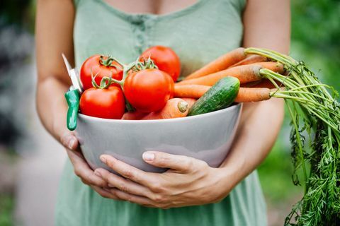 Close-up de uma mulher segurando uma tigela com legumes recém-colhidos