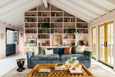 sala de estar, área de estar com paredes rosa, sofá-sofá azul, pufe de couro marrom, portas envidraçadas amarelas